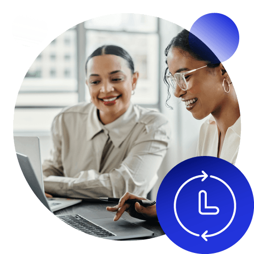 Two women smiling around a laptop.